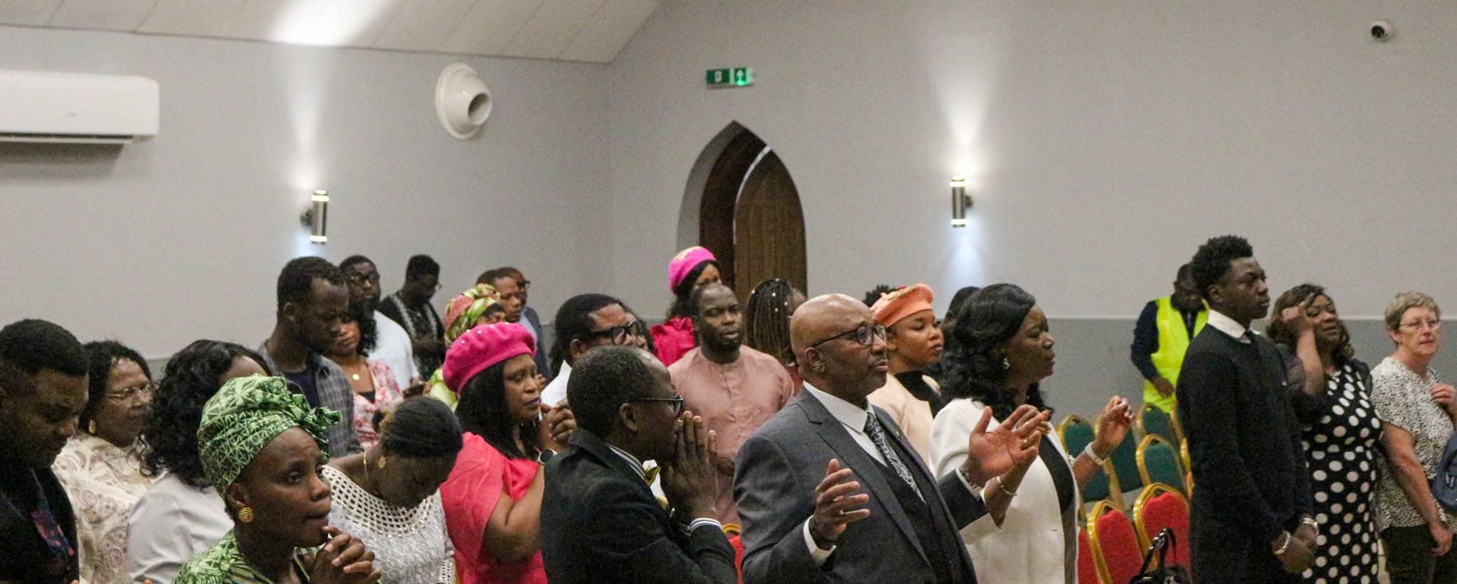 Congregation of RCCG Grace Assembly Dinnington standing in worship, hands raised